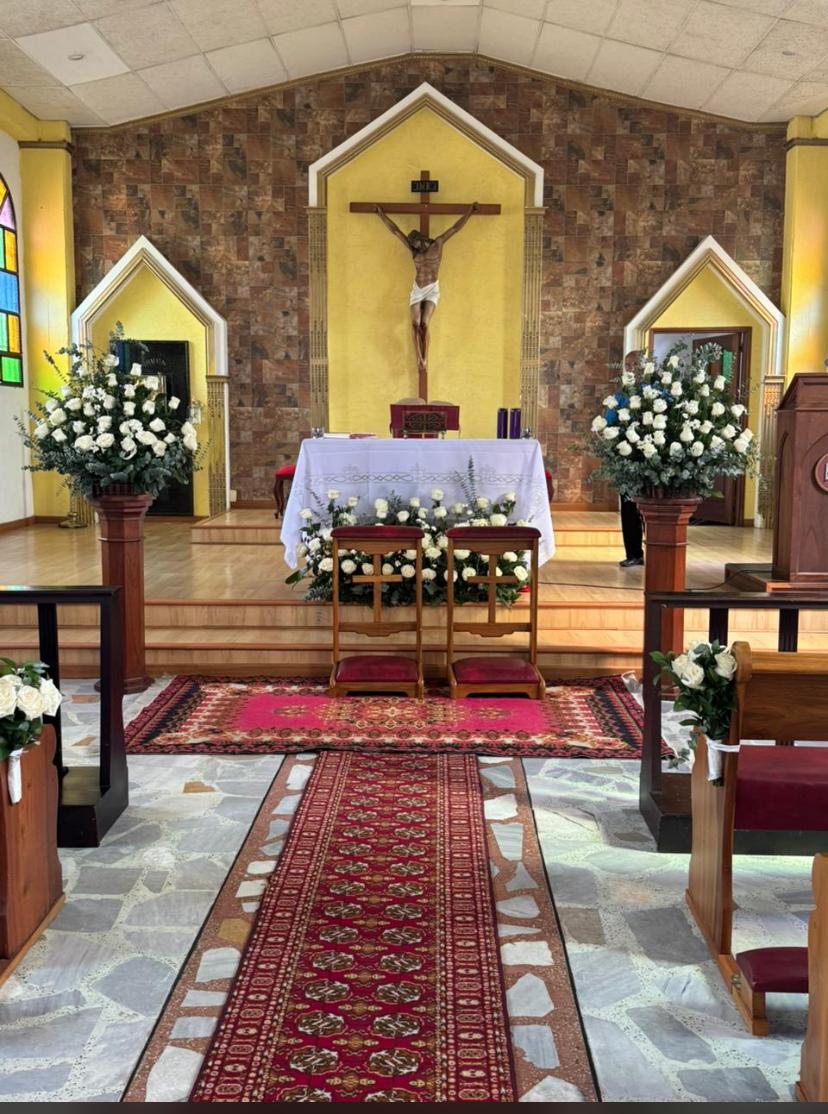 Altar de iglesia decorado con arreglos de rosas blancas y eucalipto para una boda en Manizales