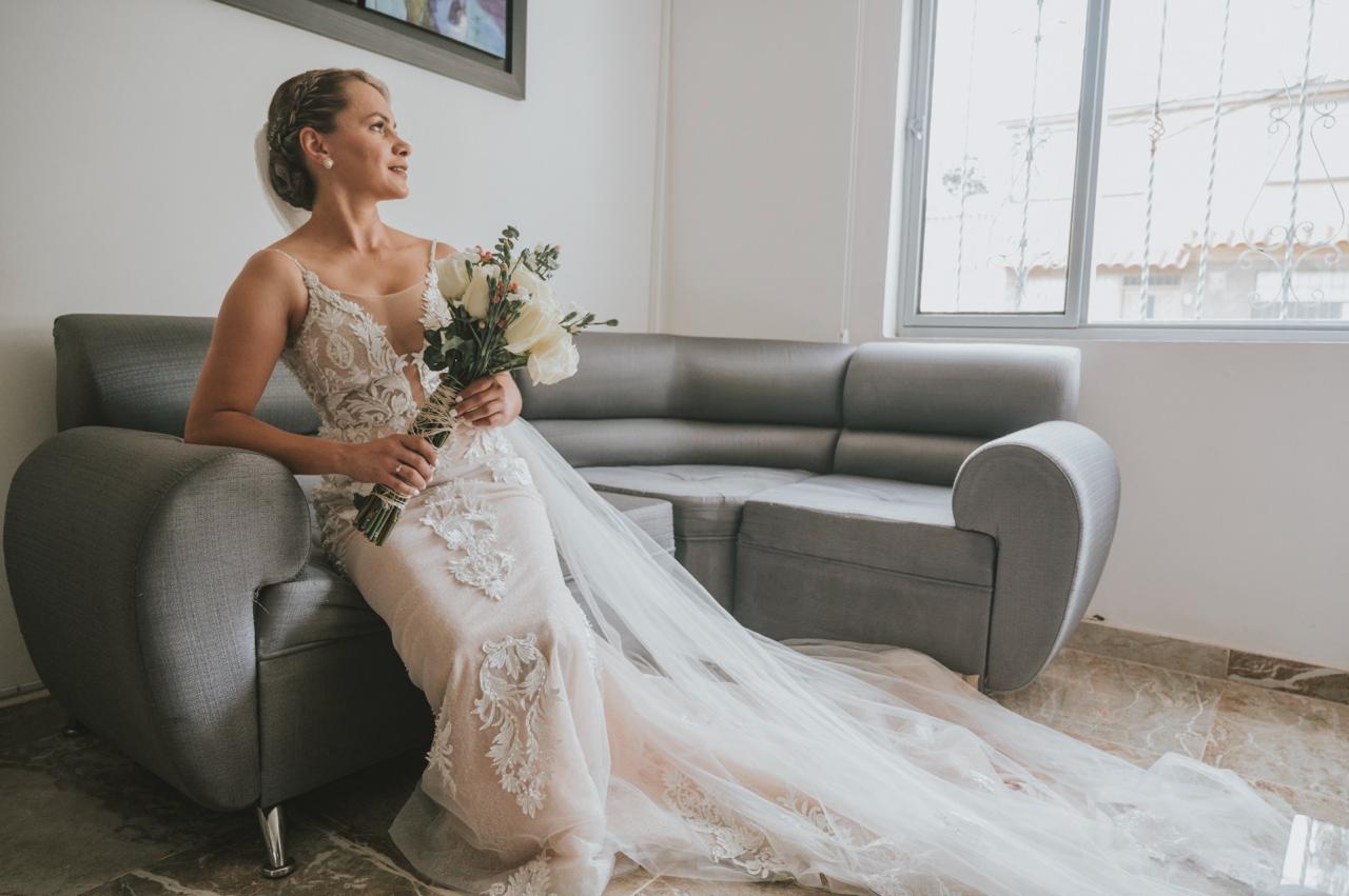Novia sentada con su ramo de rosas blancas el d&iacute;a de su boda en Manizales, decoraci&oacute;n de Rosas Don Diego